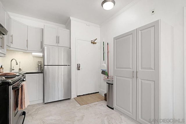 kitchen with white cabinets, appliances with stainless steel finishes, sink, backsplash, and ornamental molding