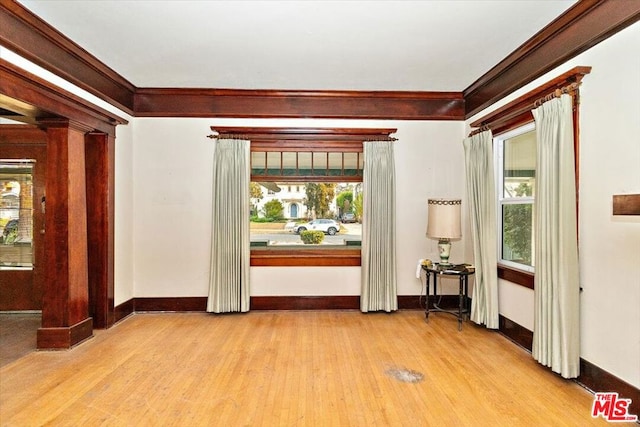 interior space with light hardwood / wood-style flooring, crown molding, and ornate columns