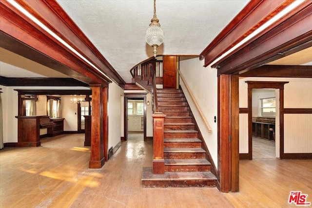 stairway featuring wood-type flooring, ornamental molding, and a chandelier