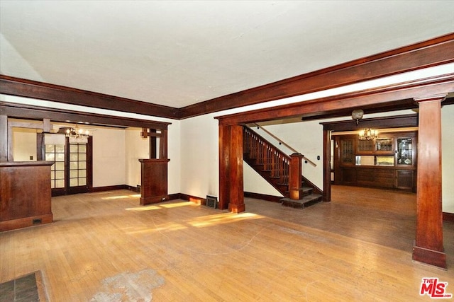 unfurnished living room featuring decorative columns and light wood-type flooring