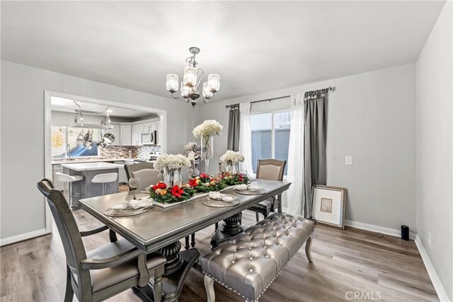 dining area with light wood-type flooring, an inviting chandelier, and sink