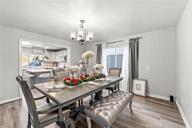 dining area with sink, a chandelier, and light hardwood / wood-style flooring