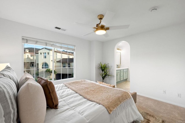 bedroom featuring light carpet, ceiling fan, and connected bathroom