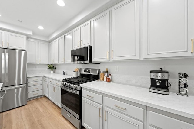 kitchen featuring light hardwood / wood-style floors, light stone counters, white cabinets, and stainless steel appliances