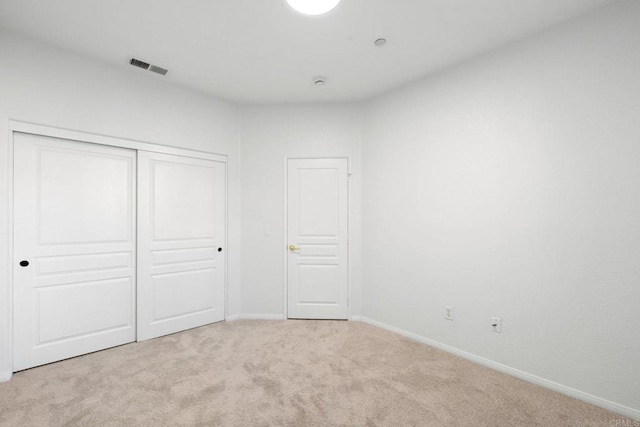 unfurnished bedroom featuring light colored carpet and a closet