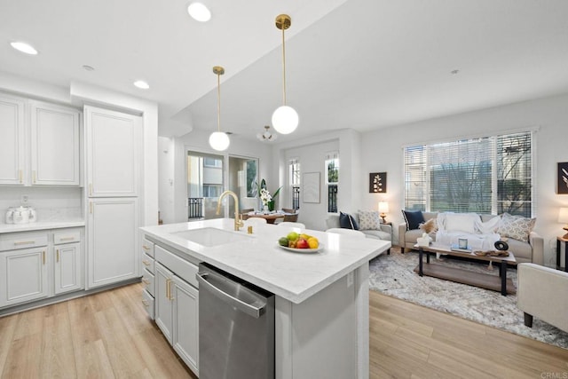 kitchen featuring decorative light fixtures, stainless steel dishwasher, sink, an island with sink, and white cabinets