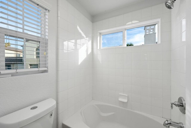 bathroom featuring toilet and tiled shower / bath