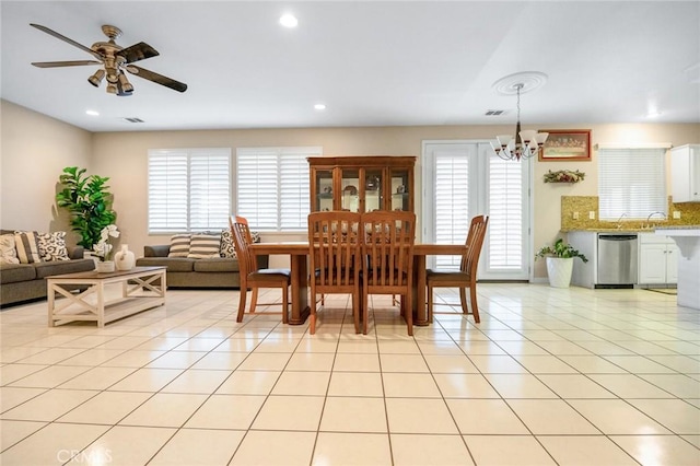 tiled dining room featuring ceiling fan with notable chandelier