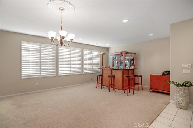 kitchen with pendant lighting, an inviting chandelier, kitchen peninsula, light colored carpet, and a breakfast bar area