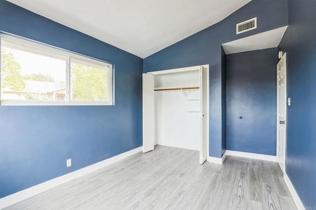 unfurnished bedroom with light hardwood / wood-style flooring, a closet, and vaulted ceiling