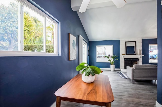 living room featuring lofted ceiling, a brick fireplace, a wealth of natural light, and hardwood / wood-style floors