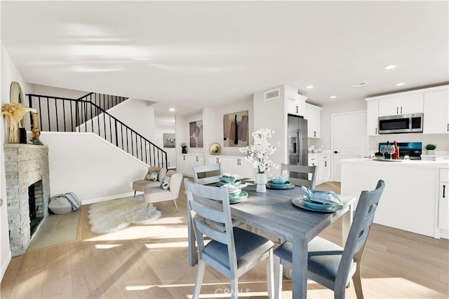 dining room featuring light wood-type flooring and a fireplace