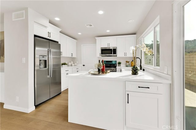 kitchen featuring light hardwood / wood-style floors, white cabinets, and appliances with stainless steel finishes