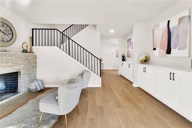 entryway with a stone fireplace and light hardwood / wood-style flooring