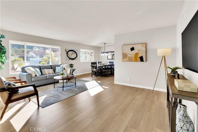 living room featuring light wood-type flooring and an inviting chandelier