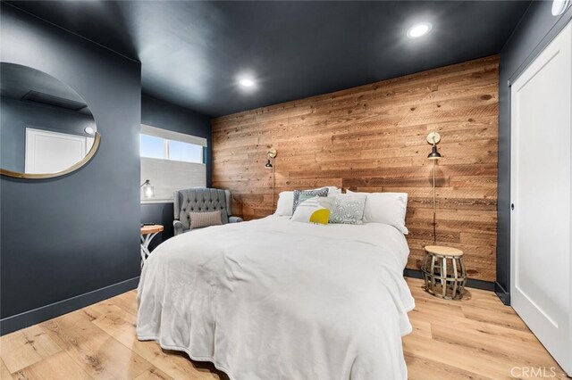 bedroom featuring light wood-type flooring and wood walls