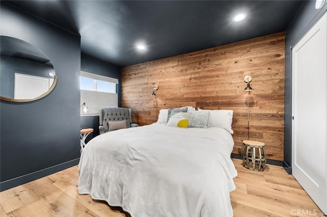 bedroom with wooden walls and light hardwood / wood-style flooring