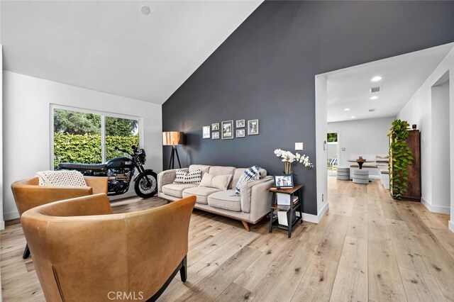 living room featuring high vaulted ceiling and light hardwood / wood-style floors