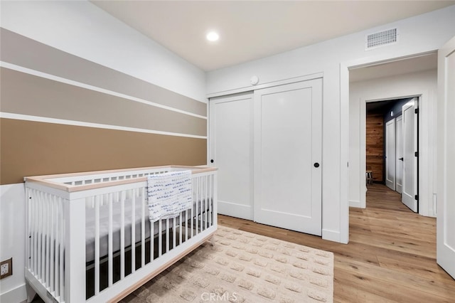 unfurnished bedroom featuring light wood-type flooring, a closet, and a crib