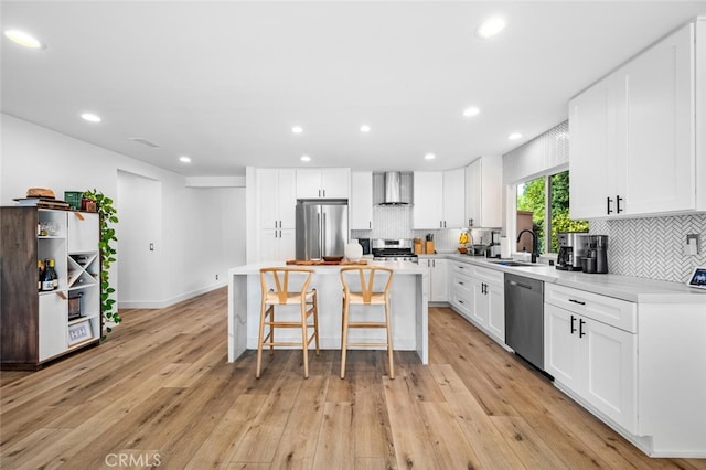 kitchen featuring a kitchen island, appliances with stainless steel finishes, white cabinets, and wall chimney exhaust hood