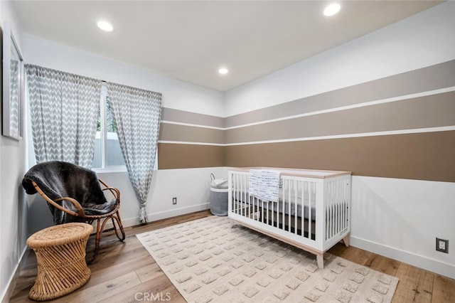 bedroom with light hardwood / wood-style floors and a crib