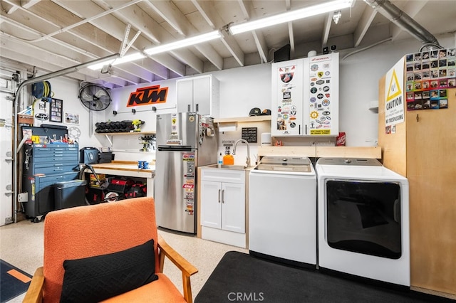 laundry area featuring sink, washer and clothes dryer, and a workshop area