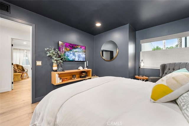 bedroom with multiple windows and light hardwood / wood-style flooring