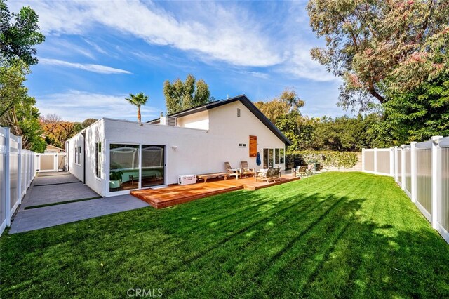 back of property with a yard and a wooden deck