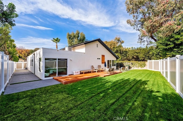 rear view of property featuring a deck and a lawn