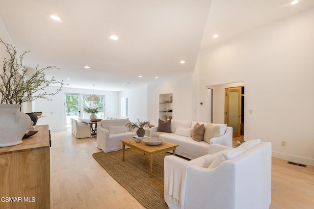 living room featuring a towering ceiling and light wood-type flooring