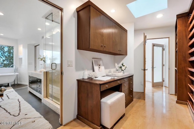 interior space with a skylight and light hardwood / wood-style floors