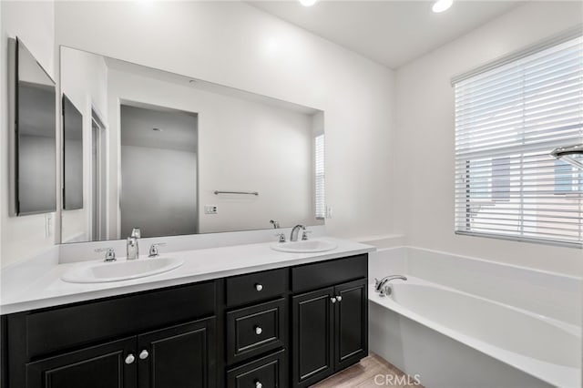 bathroom with a tub to relax in, wood-type flooring, and vanity