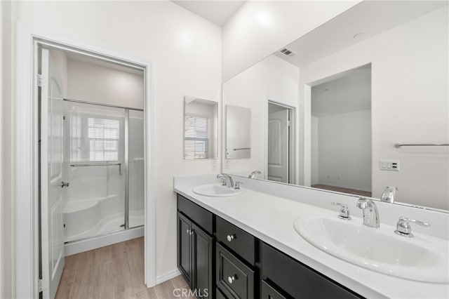 bathroom featuring hardwood / wood-style floors, a shower with door, and vanity