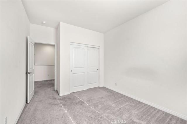 unfurnished bedroom featuring light carpet and a closet