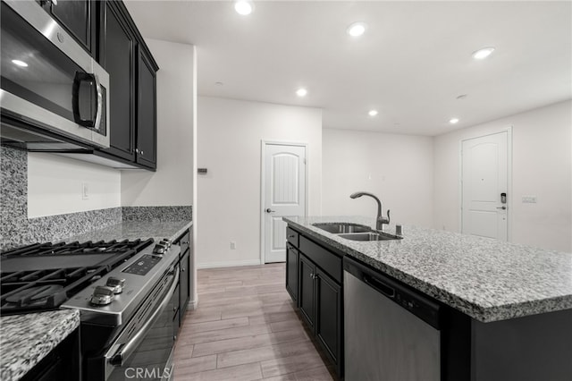 kitchen featuring light stone countertops, appliances with stainless steel finishes, sink, and an island with sink