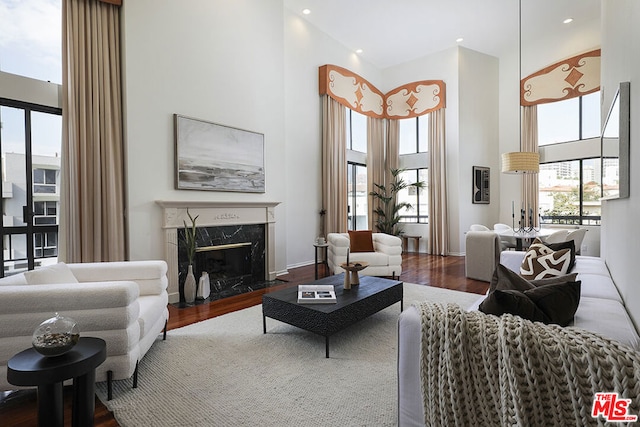 living room with a high ceiling, dark hardwood / wood-style floors, and a premium fireplace