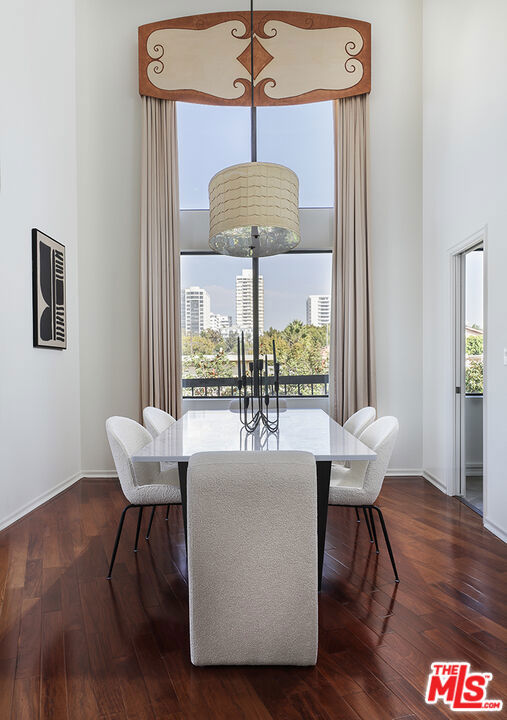 dining room with a high ceiling, plenty of natural light, and dark hardwood / wood-style flooring