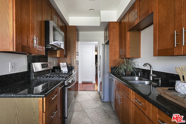 kitchen featuring dark stone counters, appliances with stainless steel finishes, sink, and light tile patterned flooring