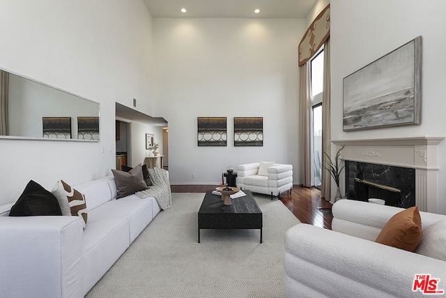 living room with a high ceiling, wood-type flooring, and a premium fireplace