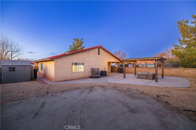 back house at dusk with a patio area, central air condition unit, an outdoor hangout area, and a storage unit