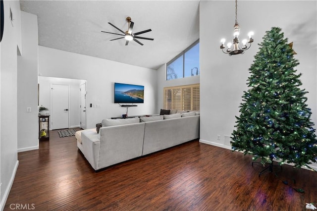 living room featuring dark wood-type flooring, ceiling fan with notable chandelier, and high vaulted ceiling