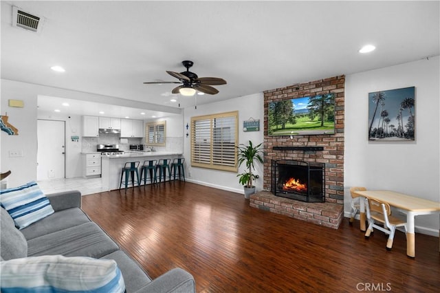 living room featuring ceiling fan, a fireplace, and dark hardwood / wood-style floors