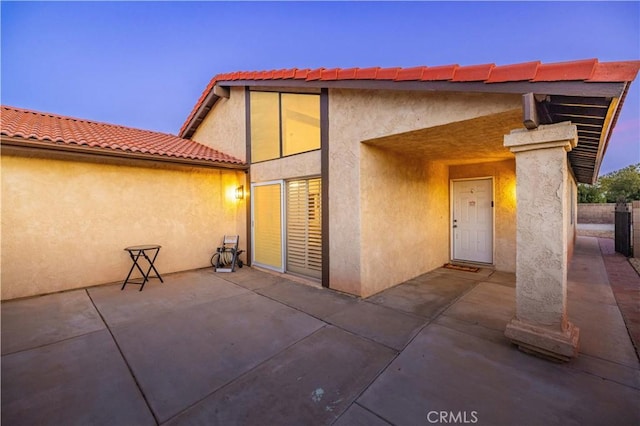 exterior entry at dusk featuring a patio area