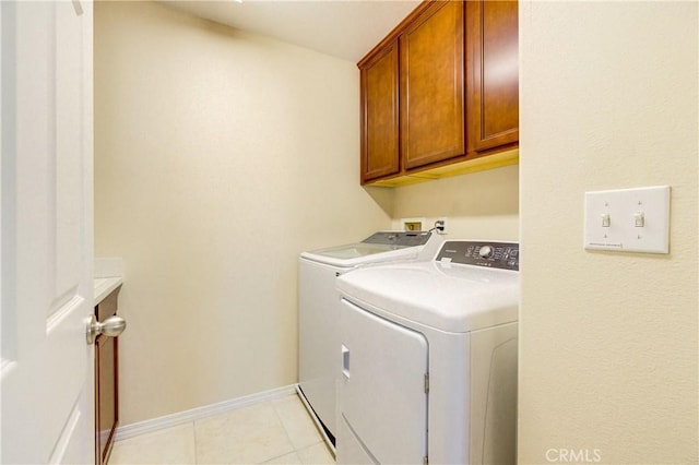 washroom with washing machine and dryer, light tile patterned flooring, and cabinets