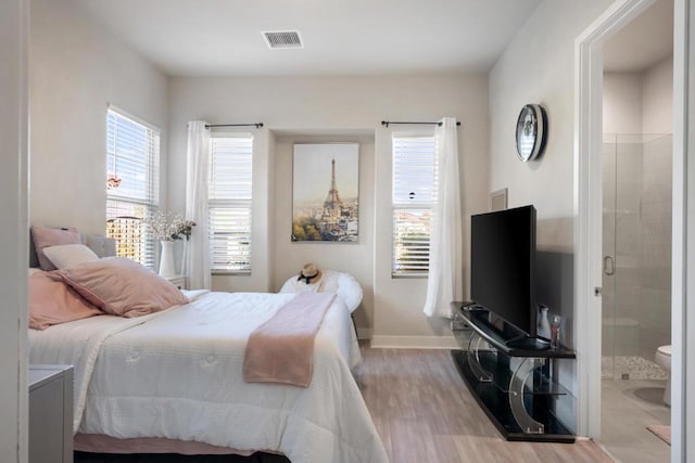 bedroom featuring ensuite bathroom and light wood-type flooring