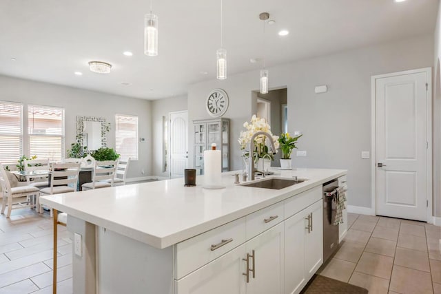 kitchen with pendant lighting, sink, light tile patterned floors, an island with sink, and white cabinets