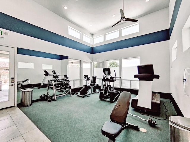 exercise room featuring ceiling fan, light carpet, and a towering ceiling