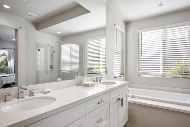 bathroom featuring plus walk in shower, vanity, and a healthy amount of sunlight