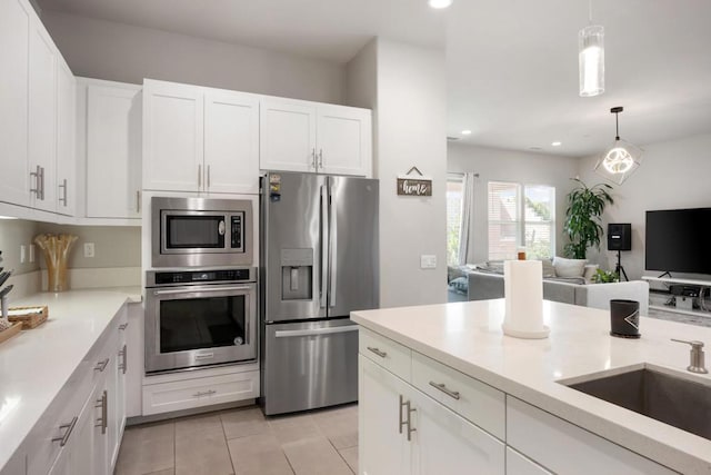 kitchen with white cabinetry, stainless steel appliances, sink, hanging light fixtures, and light tile patterned floors