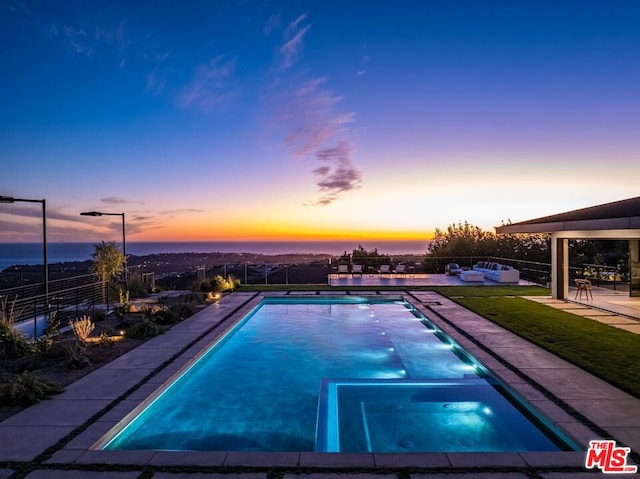 pool at dusk with a patio area